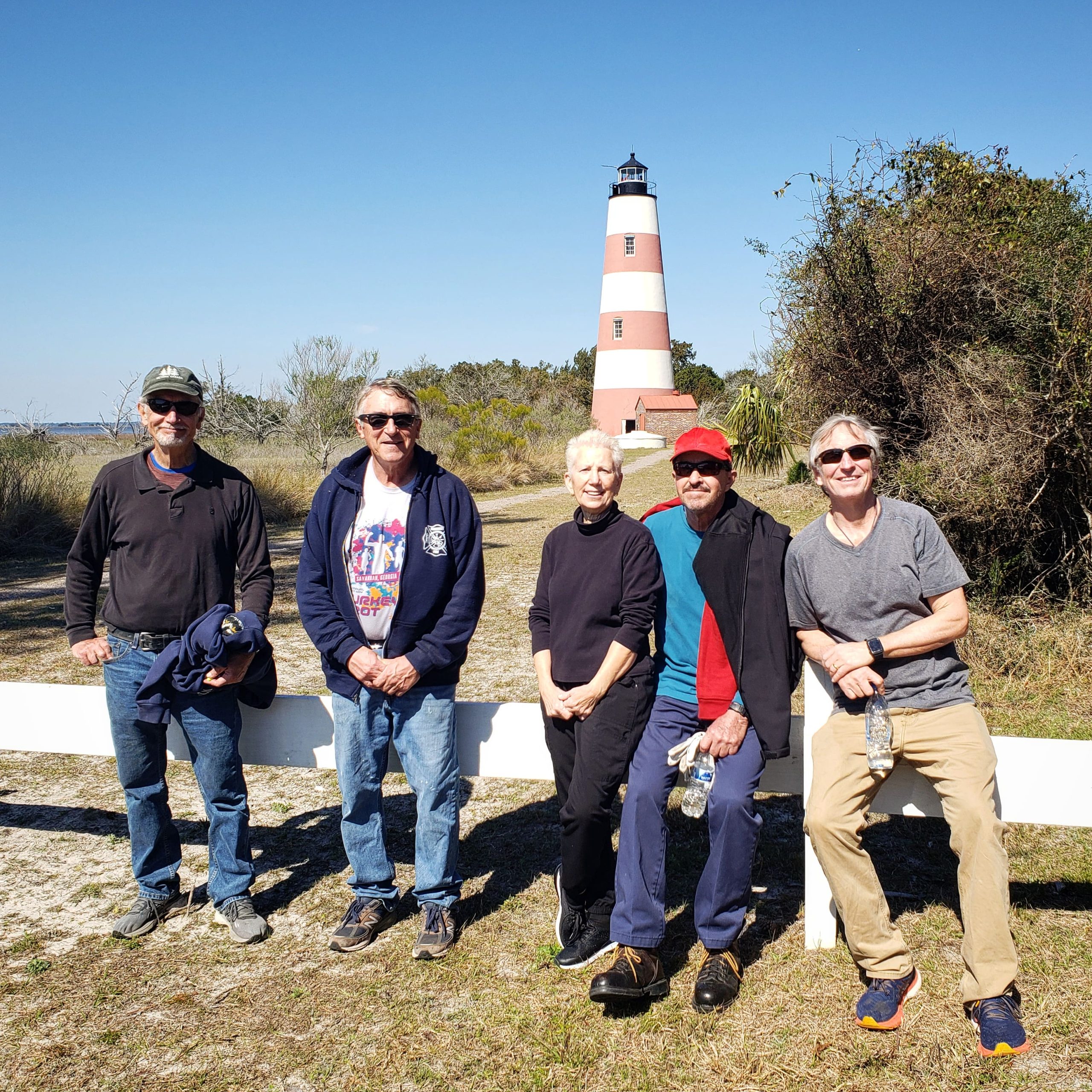 A group of smiling people posing in front of a lighthouse